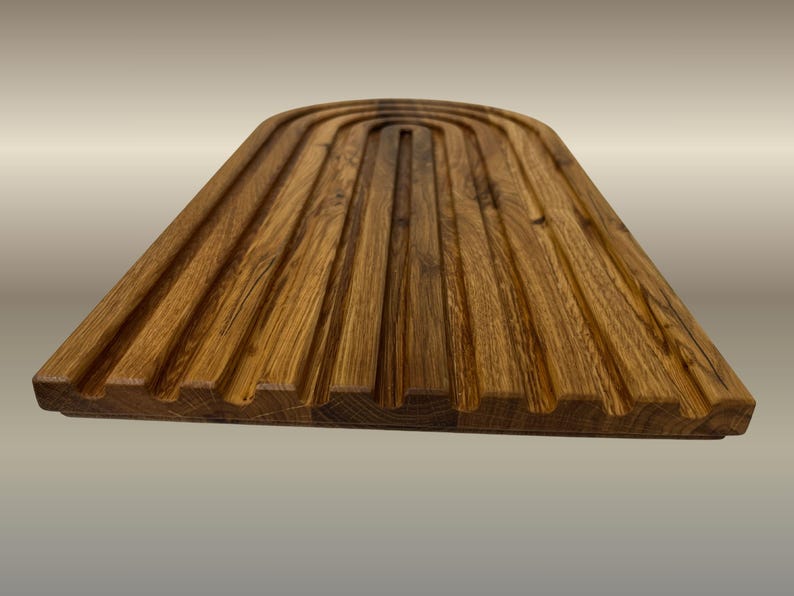 May include: A wooden breadboard with a grooved surface. The board is made of light brown wood and has a rectangular shape with a curved top. The grooves run lengthwise, creating a textured appearance. The board is designed for serving bread.