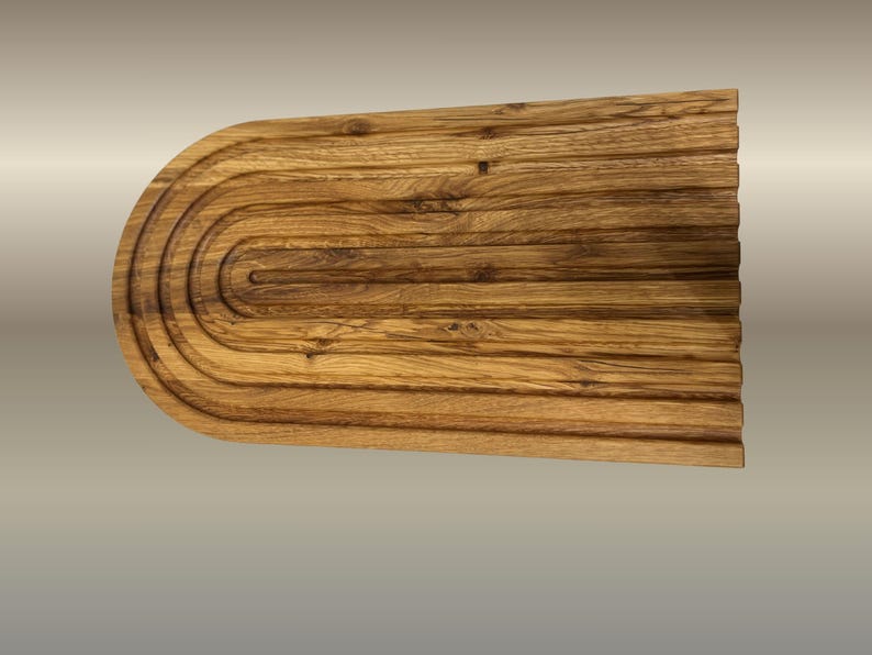 May include: A wooden cutting board with a unique design. The board is rectangular with a rounded end and features a series of concentric grooves. The wood has a warm, natural tone with visible grain, and the board measures approximately 18 inches long.