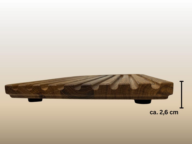 May include: A wooden breadboard with a grooved surface and rounded edges. The board is approximately 1 inch thick and rests on two small black feet. The wood has a warm, natural tone.