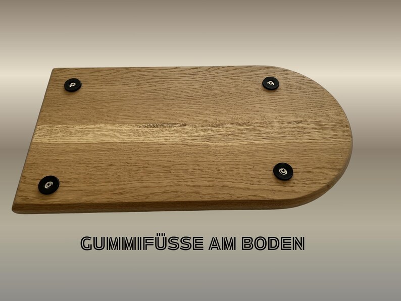 May include: A light brown wooden cutting board with a rounded edge and four black rubber feet. The text "Gummif&uuml;&szlig;e am Boden" is printed in black at the bottom of the image.