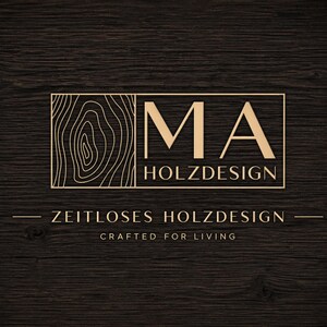 May include: A gold-colored logo on a dark wood grain background. The logo features the letters "MA" above the word "HOLZDESIGN" within a rectangular frame. Below, the text reads "ZEITLOSES HOLZDESIGN" and "CRAFTED FOR LIVING".