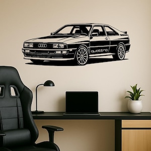 Könnte beinhalten: Schwarz-weiß Audi Quattro Auto-Wandkunst. Das Auto ist im Profil dargestellt, mit dem Wort "quattro" sichtbar. Das Bild ist an einer beigefarbenen Wand über einem schwarzen Schreibtisch mit einem schwarzen Stuhl, einem Laptop, einer Lampe und einer Topfpflanze angebracht.