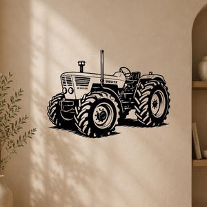 Op de afbeelding: Een zwarte muursticker met een gedetailleerde illustratie van een Deutz D 100 06 tractor. Het ontwerp toont de tractor vanuit een zijaanzicht, waarbij de grote banden met profiel, de motorkap met de merknaam Deutz en het stuurwiel zichtbaar zijn.