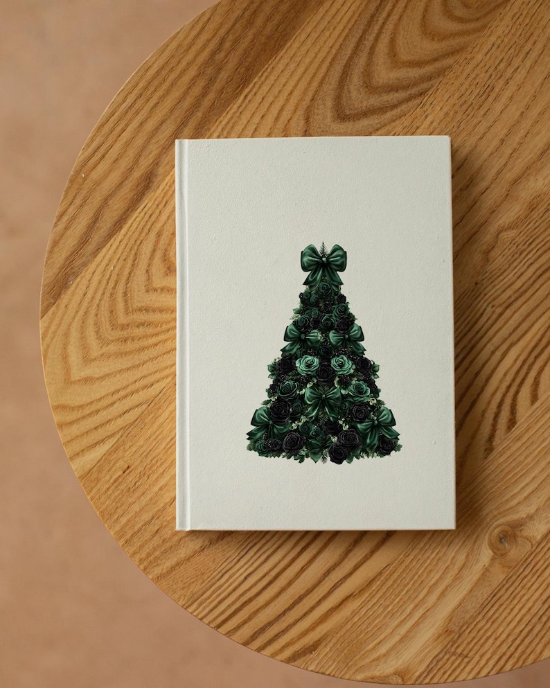 Pode incluir: Um caderno branco com um desenho de &aacute;rvore de Natal verde. A &aacute;rvore &eacute; feita de rosas e la&ccedil;os verdes. O caderno est&aacute; numa mesa de madeira.
