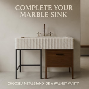 May include: A white marble sink with a fluted front, featuring a brass faucet and two handles. The sink is supported by a black metal frame on the left and a dark brown walnut vanity cabinet with a single drawer and black handle on the right. Text reads: COMPLETE YOUR MARBLE SINK. CHOOSE A METAL STAND OR A WALNUT VANITY.