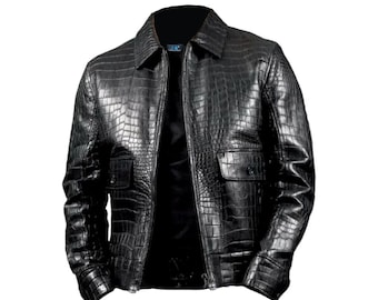 Puede incluir: Chaqueta de cuero negro con textura de piel de cocodrilo. La chaqueta tiene cuello, cierre de cremallera y dos bolsillos delanteros. El diseño incluye un patrón texturizado en toda la prenda.