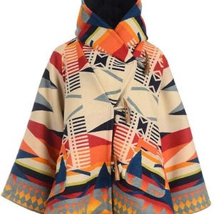May include: A colorful poncho-style coat with a geometric pattern in shades of cream, orange, red, blue, and gray. The coat features a high collar, toggle closures, and a unique design, perfect for adding a pop of color to any outfit.