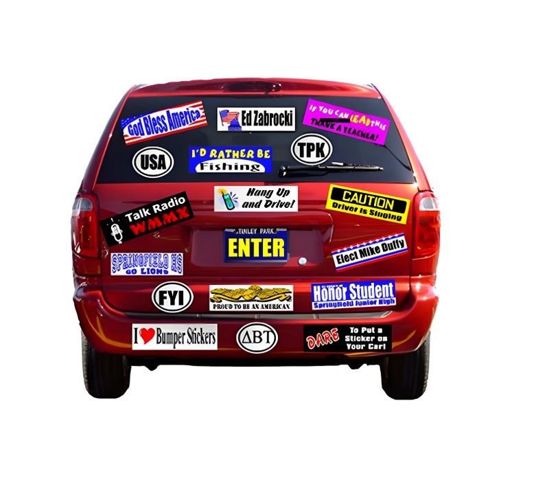 May include: A red SUV rear view covered in various rectangular and oval bumper stickers with text including God Bless America, Ed Zabrocki, I'd Rather Be Fishing, Talk Radio WMMX, Hang Up and Drive, Caution Driver Is Singing, and Honor Student.