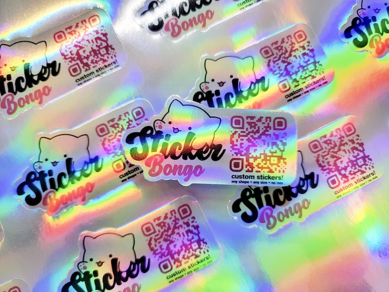 May include: A collection of iridescent holographic stickers with a cartoon cat design and the text "Sticker Bongo" and "custom stickers!" The stickers feature a QR code and are available in various shapes and sizes.