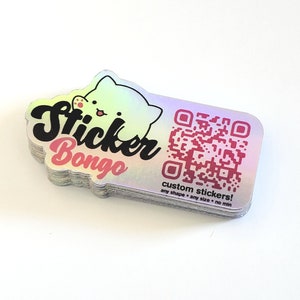 May include: A stack of iridescent holographic stickers with the text "Sticker Bongo" and a cartoon cat. The stickers also feature a QR code and the text "custom stickers! any shape - any size - no min".