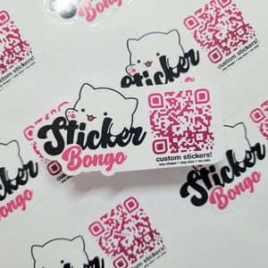 May include: A collection of white stickers with a pink and black design. The stickers feature a cartoon cat with a QR code and the text "Sticker Bongo" in a pink and black font. The text "custom stickers!" is also included on the stickers.