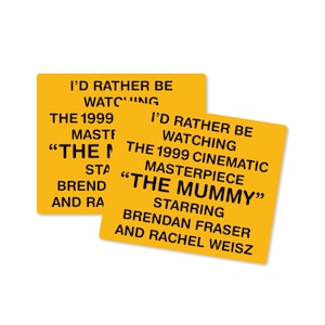 May include: Two yellow square stickers with black text. The text on the stickers reads "I'd rather be watching the 1999 cinematic masterpiece "The Mummy" starring Brendan Fraser and Rachel Weisz."