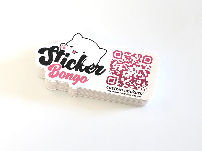 May include: A stack of white custom stickers with a pink and white cartoon cat and the text "Sticker Bongo". The stickers also feature a pink QR code with the text "custom stickers! any shape - any size - no min".