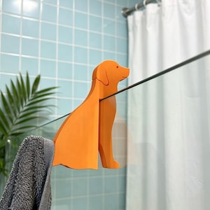 Peut inclure: Un porte-serviette orange vif en forme de chien conçu pour s'accrocher sur le bord supérieur d'une porte de douche en verre. Cet accessoire de couleur unie au fini mat présente une silhouette canine stylisée avec une encoche pour serviette.
