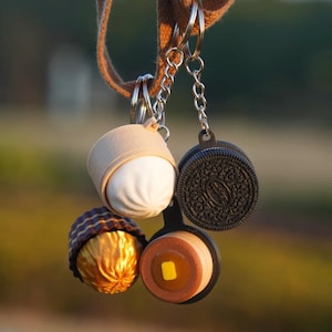 Peut inclure: Une tasse en céramique blanche avec une anse noire et le texte "But First, Coffee" en gras noir. La tasse est posée sur un fond flou, suggérant un cadre chaleureux.