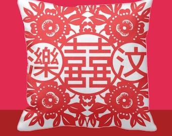 Könnte beinhalten: Quadratisches weißes Kissen mit rotem Blumendesign und chinesischen Schriftzeichen. Das Design umfasst ein zentrales Doppeltes-Glück-Symbol, umgeben von floralen Mustern und zusätzlichen Zeichen. Das Kissen hat einen roten Hintergrund.
