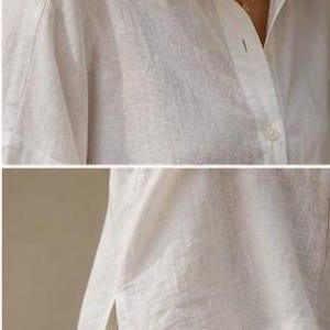 May include: A white button-down shirt with a classic collar, long sleeves, and a visible button placket. The shirt features a textured fabric, a straight hemline, and side slits at the bottom, providing a relaxed fit and a clean, simple design.