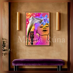 Puede incluir: Una impresión artística enmarcada que presenta el rostro de una mujer adornado con un lirio de agua blanco y flores azules. La obra de arte tiene un fondo rosa y naranja vibrante, con el texto "Magna Rúna" en la parte inferior. La impresión se muestra encima de un banco de terciopelo púrpura.