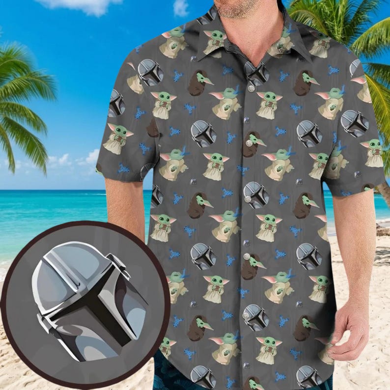 May include: Gray button-down shirt with a repeating pattern of a helmet, a character, and a creature. The shirt has short sleeves and a classic collar. The background shows a beach with palm trees and the ocean.