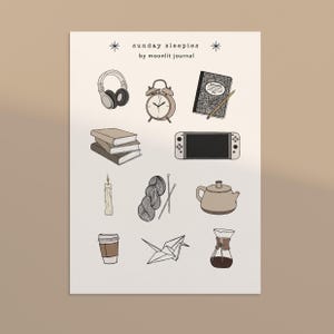 Könnte beinhalten: Illustration mit verschiedenen Gegenständen: Kopfhörer, Wecker, Notizbuch, Bücher, Spielkonsole, Kerze, Garn, Teekanne, Kaffeetasse, Origami-Kranich und Kaffeebereiter. Text: "sunday sleepies by moonlit journal."