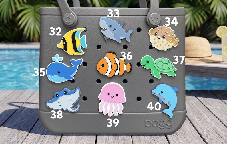 May include: A gray rubber tote bag featuring nine colorful sea creature charms attached to its perforated surface. The charms include a yellow fish, shark, pufferfish, blue whale, clownfish, sea turtle, stingray, jellyfish, and dolphin, labeled 32-40.