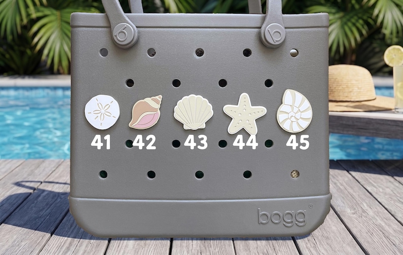 May include: A gray rubber tote bag featuring five circular holes across the front, each decorated with a different sea-themed charm labeled 41 through 45. The charms include a sand dollar, a conch shell, a scallop shell, a starfish, and a nautilus.