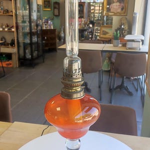 Pretty orange blown glass oil lamp on transparent pedestal