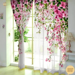 May include: White sheer curtains adorned with a floral pattern. The design showcases cascading pink flowers and green foliage, offering a light and airy feel. The floral print brings a natural and elegant touch to the window dressing.