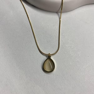 Druppelvormige ketting met vergulde crèmekleurige steen, minimalistische sieraden