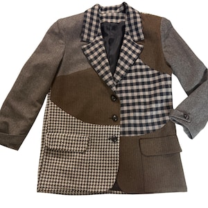 May include: A patchwork blazer in shades of brown, gray, and black. The blazer features a mix of patterns, including houndstooth, plaid, and herringbone. It has a notched lapel, three buttons, and two pockets.