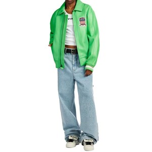 Puede incluir: Chaqueta de cuero verde brillante con cremallera, top blanco y vaqueros azul claro. La chaqueta presenta un parche con un dise&ntilde;o rojo, blanco y azul. El conjunto se completa con un cintur&oacute;n negro y zapatillas blancas.