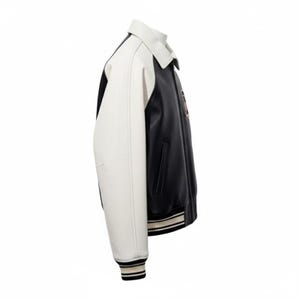 Puede incluir: Chaqueta universitaria negra y blanca con cuello y mangas blancas. La chaqueta tiene un cuerpo negro con un peque&ntilde;o emblema en el pecho. Los pu&ntilde;os y el dobladillo presentan detalles a rayas.