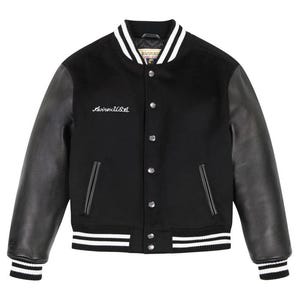 May include: Black varsity jacket with leather sleeves and white striped accents on the collar, cuffs, and hem. The jacket features the embroidered text "Avirex USA" on the chest and a button-up front.