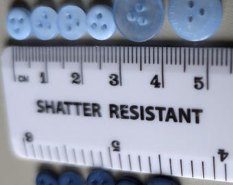 11 botones azules de diferentes tonos y tamaños, todos con 3 agujeros de costura, lo más inusual.