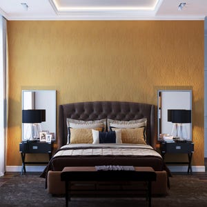 May include: A luxurious bedroom featuring a tufted headboard, a dark brown bedspread, and matching nightstands with lamps. The room has a warm color palette with a gold textured wall and a dark brown bench at the foot of the bed.