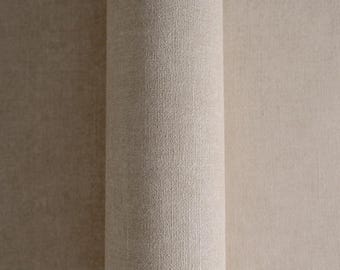 May include: Close-up of a rolled-up beige fabric, showcasing its textured surface. The fabric appears to be a neutral color, suitable for various interior design applications. The roll is tightly wound, revealing the fabric's thickness and weave.