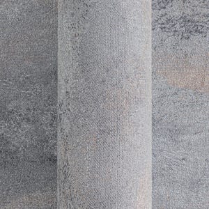 May include: Rolled-up gray rug with a textured surface. The rug has a mottled pattern with darker gray and brown accents. The close-up view highlights the woven texture and color variations.