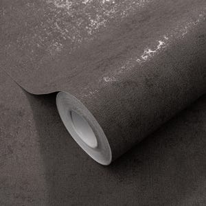 May include: A roll of dark gray wallpaper with a textured, metallic-like finish. The surface has a mottled appearance with lighter, silver-toned accents, creating a distressed, industrial aesthetic. The roll is partially unrolled, revealing the paper's edge.