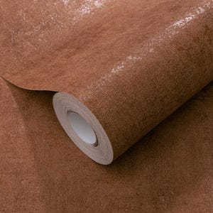 May include: A roll of brown wallpaper with a textured, distressed appearance. The paper has a metallic sheen, with lighter areas that catch the light. The roll is partially unrolled, revealing the paper's core.