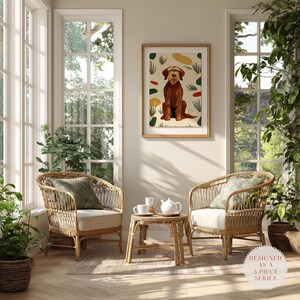Puede incluir: Una lámina de arte mural enmarcada con la ilustración de un perro de pelo duro marrón con formas abstractas verdes y rojas, sobre dos sillones de ratán claro con cojines blancos y una pequeña mesa auxiliar redonda de ratán con un juego de té.