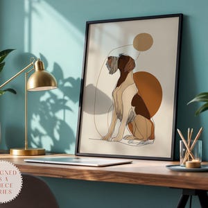 Puede incluir: Una impresión artística enmarcada con un dibujo lineal de un perro en tonos marrones, beige y blanco, con formas geométricas abstractas. La obra de arte se exhibe en un escritorio de madera con una lámpara de escritorio dorada y una planta. El texto "DESIGNED AS A 3 PIECE SERIES" es visible.