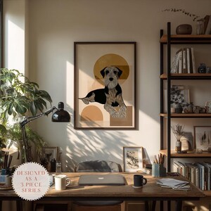 Puede incluir: Impresión artística enmarcada con una ilustración estilizada de un perro en negro, beige y crema. La obra de arte incluye formas geométricas en una paleta de colores neutros. La impresión se muestra en un escritorio de madera con un portátil, una taza y una lámpara. El texto en la imagen dice "DESIGNED AS A 3 PIECE SERIES."