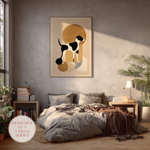 Puede incluir: Una impresión artística enmarcada con una ilustración de perro en blanco y negro sobre un fondo beige con formas geométricas. La obra de arte está encima de una cama con ropa de cama gris. El texto "DESIGNED AS A 3 PIECE SERIES" está en un círculo en la parte inferior.