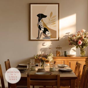May include: A framed art print featuring a stylized black and white dog illustration. The artwork is set against a neutral background with abstract shapes and botanical elements. The print is displayed above a dining table set for a meal.