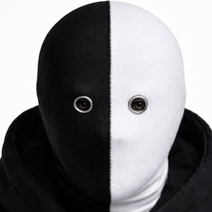 May include: A person wearing a black hooded jacket and blazer, with a mask that is split vertically into black and white halves. The mask has eye holes with metal rings around them. neo robot