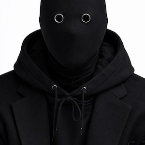 May include: A person wearing a black balaclava with silver eyelets, a black turtleneck, a black hoodie, and a black blazer. The image is set against a white background. neo robot