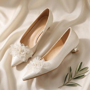 Chic and elegant wedding heels featuring a delicate floral design with soft tulle accents and pearl details. These bridal shoes are designed with a comfortable kitten heel for added height and style. Perfect for brides looking for a sophisticated yet comfortable shoe for their big day.