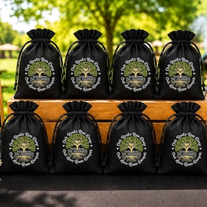 May include: Black drawstring favor bags with a tree design and the text "Our Roots Run Deep, Our Love Runs Deeper". The bags are arranged on a wooden surface with two framed signs that read "Good Food, Good People, Good Times" and "Together is our favorite place to be".