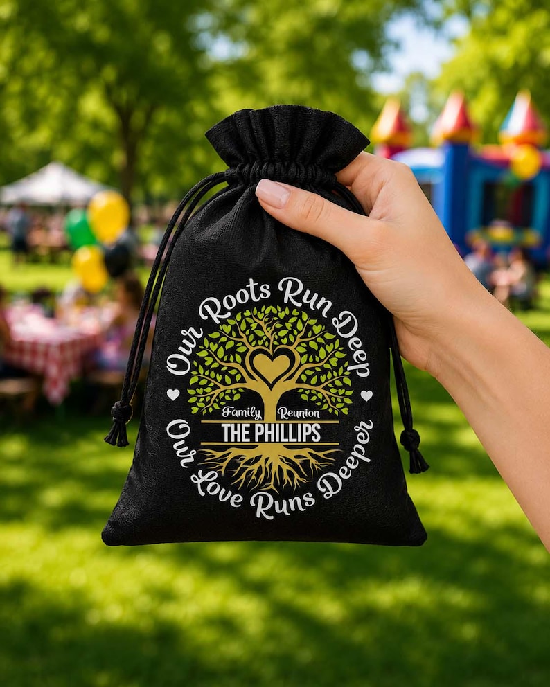 May include: Black drawstring bag with the text "Our Roots Run Deep, Our Love Runs Deeper" surrounding a tree graphic with a heart and the words "Family Reunion THE PHILLIPS". The bag is held by a hand.