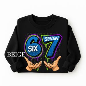 May include: Black sweatshirt with the numbers "6" and "7" in blue, outlined in purple and green, with the word "SIX" inside the "6". The sweatshirt has the word "BEIGE" in white on the bottom left.